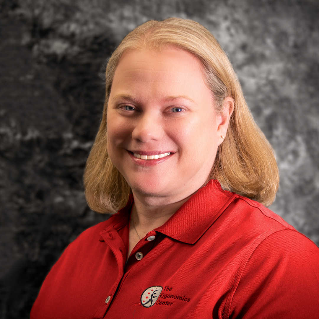 A headshot of Julia Abate standing in front of a gray-marbled background.