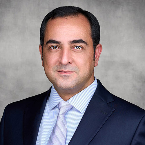 A headshot of Mohammad Hosseinian standing in front of a tan background.