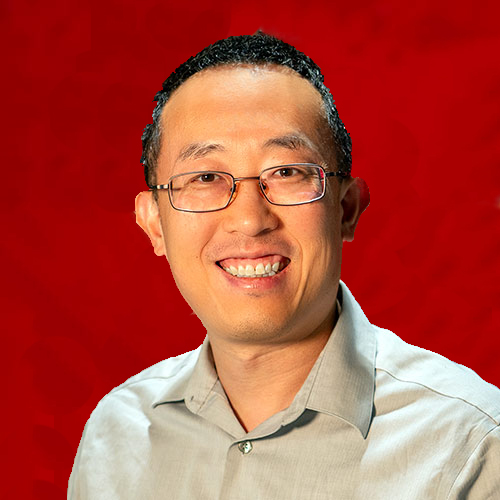 A headshot of Renran Tian standing in front of a red background in Fitts-Woolard Hall.